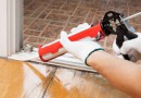 Worker applies silicone caulk on the wooden floor for sealant wa
